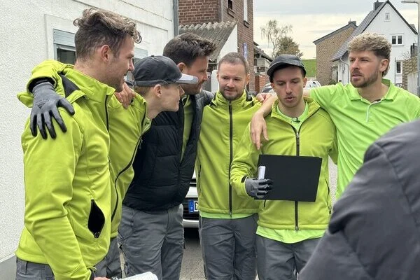 Die Youtuber des Kanals "Die Rinos" stehen im Halbkreis eng zusammen vor einem Haus und haben die Arme über die Schultern des jeweils anderen gelegt