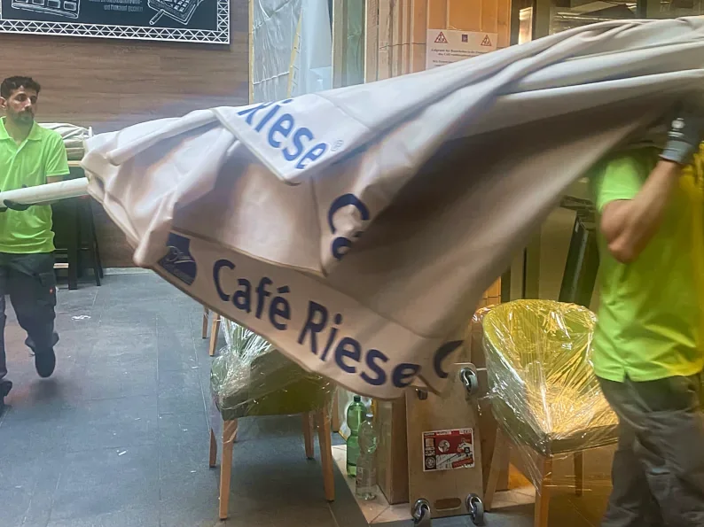 Umzugshelfer tragen einen Café Riese Schirm