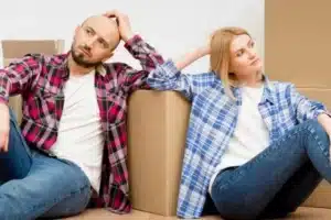 Ein Mann und eine Frau sitzen vor Umzugskartons auf dem Boden