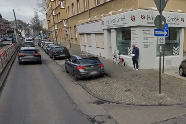 Straßenecke mit geparkten Autos, einem stehenden Mann und einem Gebäude in Köln Nippes