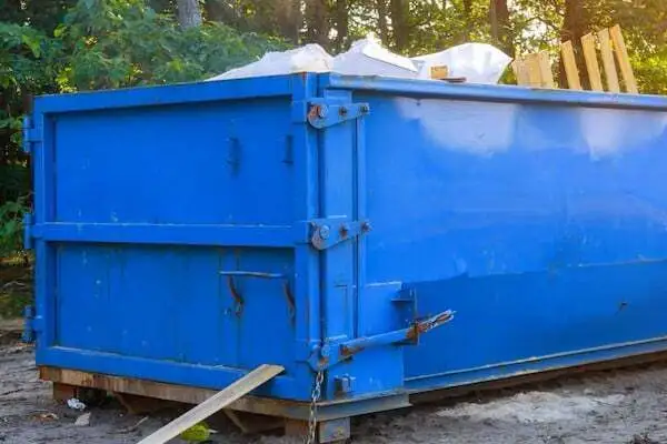 Großer blauer Container für Sperrmüll mit offenem Deckel und sichtbaren weißen Säcken und Holzteilen im Inneren