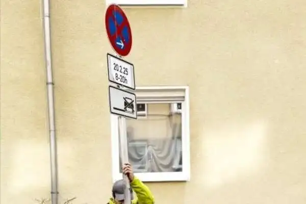 Umzugshelfer stellt ein Halteverbotsschild vor einer Hauswand auf