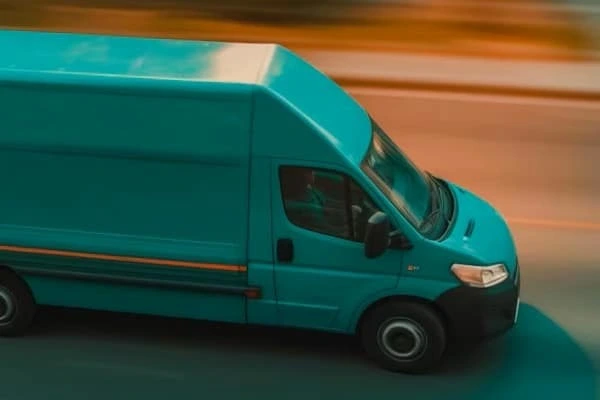 Blauer Transporter fährt auf Straße mit unscharfem Hintergrund