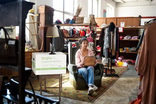 Eine Frau sitzt auf einem Sessel in einem Second-Hand-Geschäft.