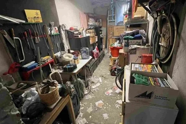 Vollgestellter Kellerraum mit Regalen, Kartons, Werkzeugen und Fahrrädern an den Wänden