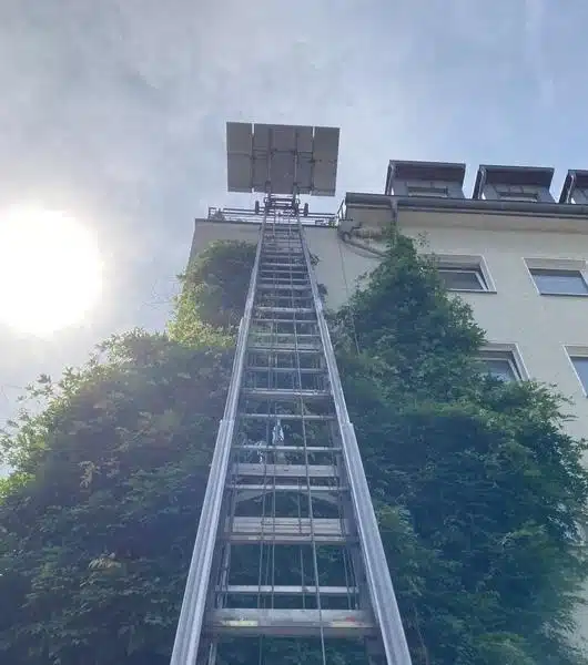 Untenansicht eines Möbellifts, der an einer Hauswand angebracht ist.