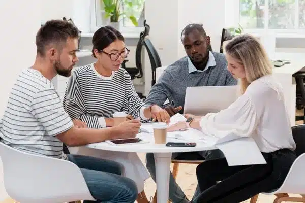 Arbeitskollegen- und kolleginnen sitzen gemeinsam an einem Tisch.