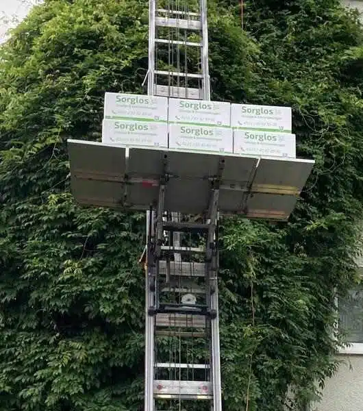 Mehrere Umzugskartons der Firma Sorglos Umzüge & Entrümpelungen stehen auf der Plattform eines Außenlifts.