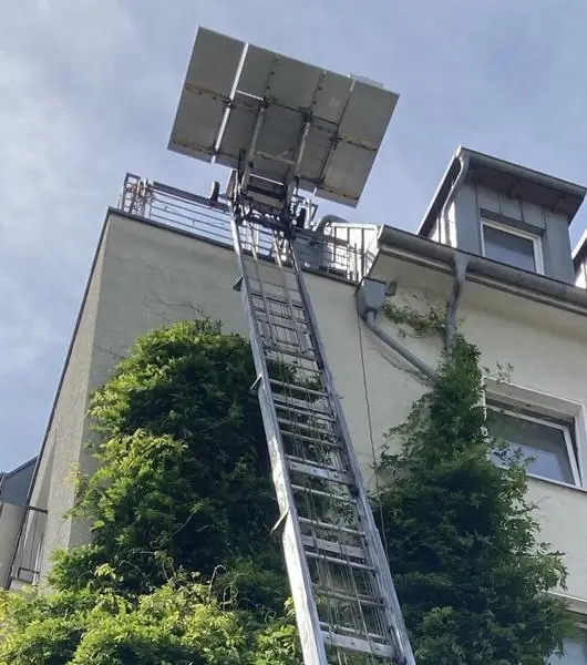 Untenansicht eines Möbellifts, der an einer Hauswand angebracht ist.