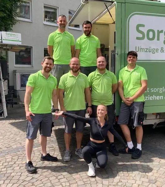 Das Umzugsteam der Firma Sorglos Umzüge & Entrümpelungen mit Lisa Küppers vor einem Umzugstransporter, dahinter ein Möbellift.