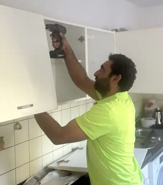 Ein Sorglos-Mitarbeiter demontiert einen Hochschrank in einer Küche