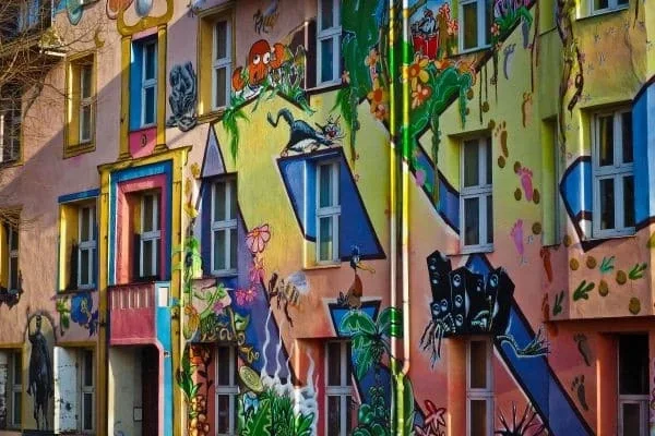 Fassadenwand mit buntem Wandgemälde aus Pflanzen, Tieren und abstrakten Formen an einem mehrstöckigen Gebäude in Düsseldorf Flingern