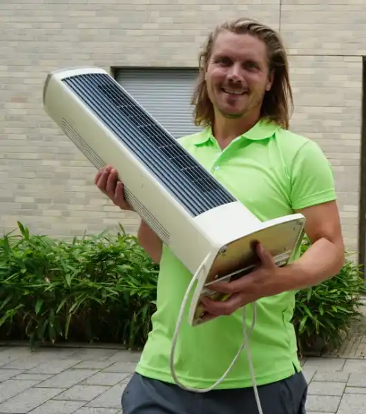 Entrümpeler in grünem Poloshirt trägt einen alten Turmventilator