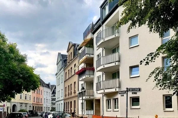 Straßenszene mit mehrstöckigen Wohnhäusern, parkenden Autos und Bäumen an der Goerresstraße in Düsseldorf-Benrath