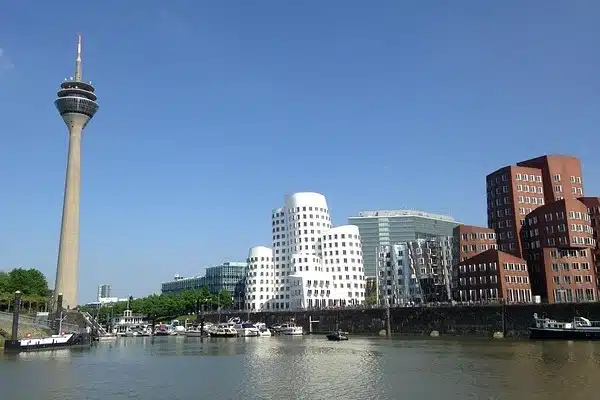 Blick auf den Rheinhafen in Düsseldorf mit Rheinturm, markanten modernen Gebäuden und Booten im Wasser