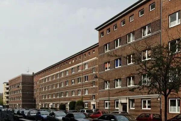 Lange mehrstöckige Backsteinwohnhauszeile mit zahlreichen Fenstern und parkenden Autos davor in der Suitbertusstraße in Düsseldorf Bilk