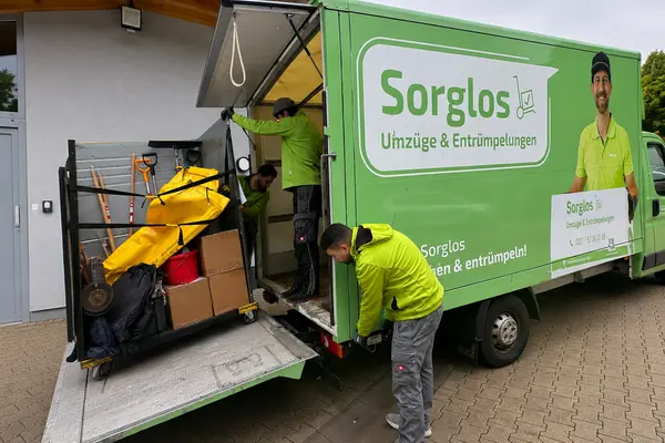 Zwei Umzugshelfer laden einen DHL-Rollwangen in das Sorglos-Mobil